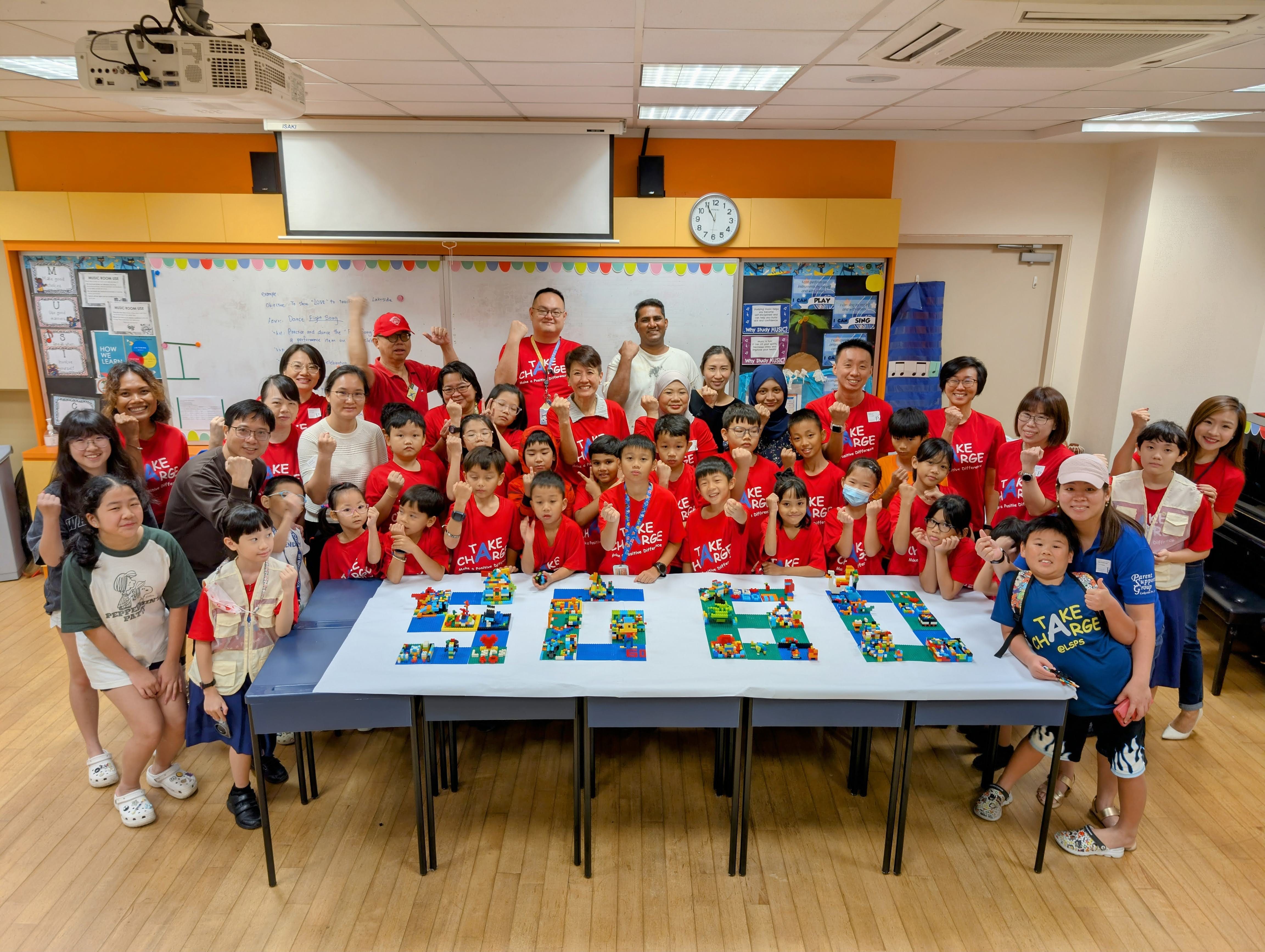 Everyone involved in the workshop take a heartwarming group photo together standing behind their collective brick art